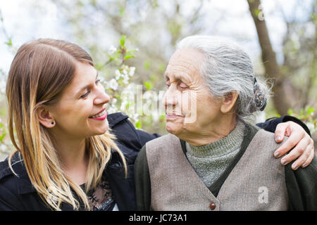 Immagine di un felice donna anziana con il suo allegro caregiver outdoor primavera Foto Stock