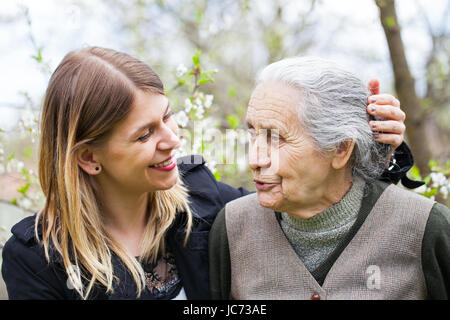 Immagine di un felice donna anziana con il suo allegro caregiver outdoor primavera Foto Stock