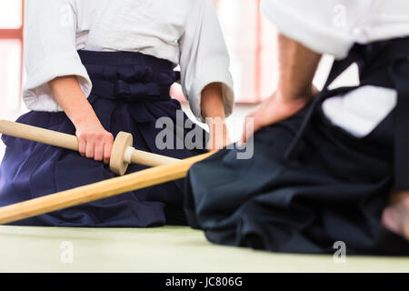 L uomo e la donna in combattimenti con le spade di legno a Aikido la formazione nella scuola di arti marziali Foto Stock