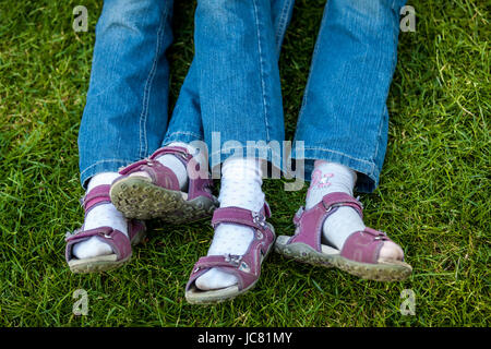 Closeup colpo di gambe simile in sandali di due gemelle Foto Stock