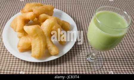 Snack e Dessert, cinese tradizionale snack fritti Doughstick sulla piastra bianca servito con tè verde latte di semi di soia. Foto Stock