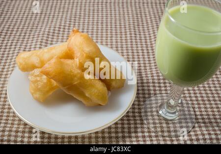 Snack e Dessert, cinese tradizionale snack fritti Doughstick su una piastra bianca servito con tè verde latte di semi di soia. Foto Stock