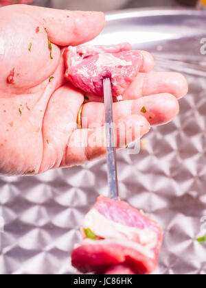 Primo piano di uno chef entrando in pezzi di carne su uno spiedino, rendendo shish kebab Foto Stock