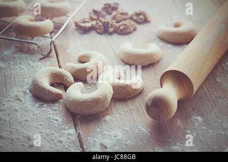 Crescent vaniglia cookies con un po' di farina, noci e perno di rotolamento su di un tavolo di legno Foto Stock