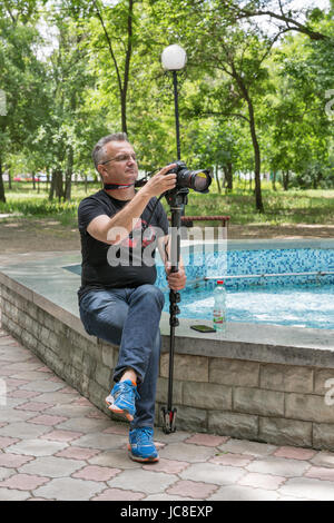 VOZNESENSK, Ucraina - 02 giugno 2017: famoso videografo ucraino Andriy Melko è ripresa con Canon 5D Mark III fotocamera monopiede e nel parco della città dur Foto Stock