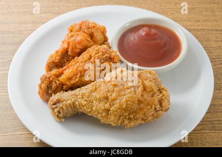 La cucina e il cibo, una piastra di piccole e grandi dimensioni fritti croccanti ali di pollo servito con salsa di pomodori sul tavolo di legno. Foto Stock