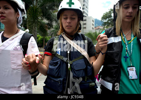 Caracas, Venezuela. 14 Giugno, 2017. Volontari provenienti da Università Centrale di Caracas che forniscono il primo aiuto durante le proteste contro il governo, pregare insieme prima di una missione a Caracas, Venezuela, 14 giugno 2017. Il gruppo indossa caschi bianco con una croce verde. Foto: Manaure Quintero/dpa/Alamy Live News Foto Stock