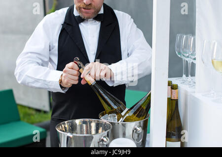 Professional cameriere di aprire una bottiglia di vino con cavatappi. Foto Stock