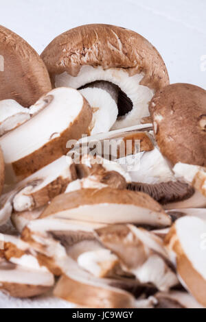 Frische Steinchampignons Champiggnons im ganzen und in Scheiben geschnitten auf einem weißen Holzbrett Foto Stock