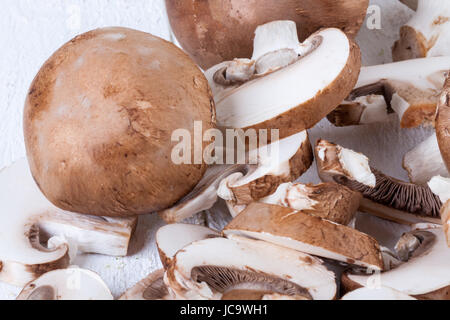 Frische Steinchampignons Champiggnons im ganzen und in Scheiben geschnitten auf einem weißen Holzbrett Foto Stock