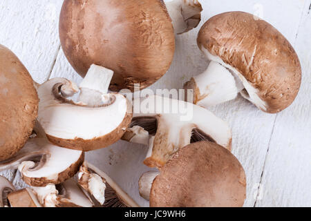 Frische Steinchampignons Champiggnons im ganzen und in Scheiben geschnitten auf einem weißen Holzbrett Foto Stock