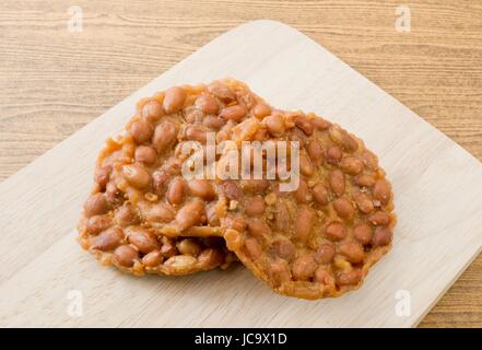 Deliziosi Crackers di arachidi realizzato da o di arachidi arachide sul tagliere di legno, spuntino Tailandese di fibra dietetica, vitamine e minerali. Foto Stock