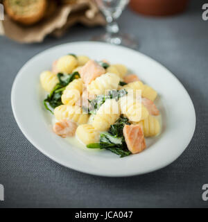 Il salmone è servita con italiano saltato gnocchi di pasta e basilico su un piatto di forma ovale per la deliziosa cucina mediterranea. Foto Stock