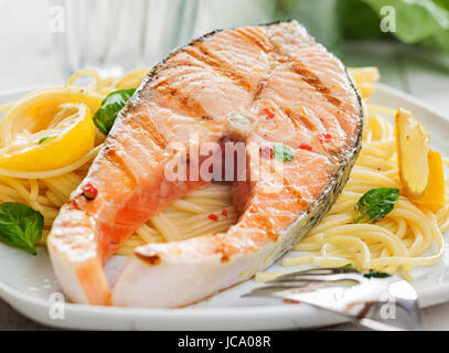 Gourmet salmone alla griglia bistecca di filetto o su un letto di italiano linguine con basilico fresco e limone, vista ravvicinata Foto Stock