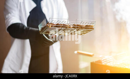 Cuoco prepara la carne sulla griglia Foto Stock