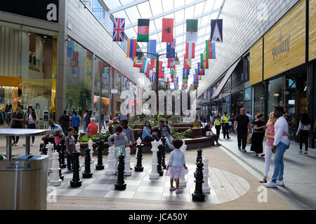I bambini stanno giocando a scacchi giochi in Westfield Stratford City shopping centre; bandiere del mondo sono appesi sopra lungo il corridoio Foto Stock