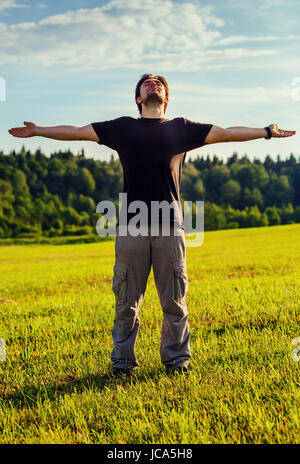 Giovane uomo godendo di buone condizioni meteorologiche e la sensazione di essere libero e positivo sulla natura Foto Stock