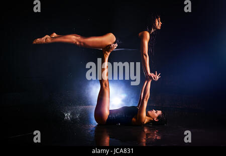 Due donne ginnasti facendo trick acrobatici in acqua studio Foto Stock