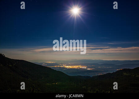 Night view with bright moon from mountains to lights and town Foto Stock