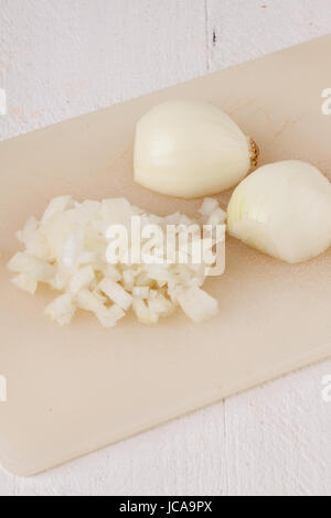 Weiße und rote Zwiebeln geschält und mit Schlale als ganzes und in würfeln Brunoise als Nahaufnahme auf Schneidebrett Foto Stock