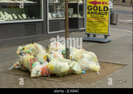 Giallo sacchi per rifiuti riciclabili in attesa di raccolta su un marciapiede nella parte anteriore del negozio, Mainz, Germania Foto Stock