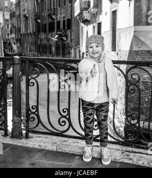 Venezia. Itinerario insolito. A piena lunghezza Ritratto di bambino moderno a Venezia, Italia in inverno mostra pollice in alto Foto Stock