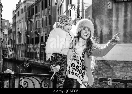 Venezia. Itinerario Insolito. Sorridendo moderna madre e figlia di viaggiatori a Venezia, Italia in inverno puntando verso qualcosa di Foto Stock