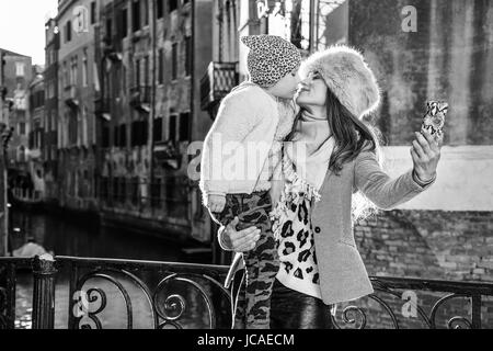 Venezia. Itinerario Insolito. Sorridendo moderna madre e figlia di viaggiatori a Venezia, Italia in inverno con lo smartphone tenendo selfie Foto Stock