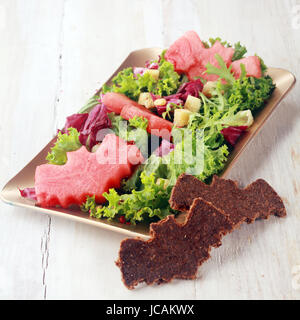 Insalata di Halloween con Bat guarnizione sagomata su sfondo di legno, immagine quadrata Foto Stock