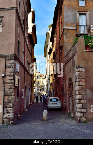 Stretta viuzza acciottolata con automobili parcheggiate sul lato e i suoi edifici colorati, Roma, Italia Foto Stock