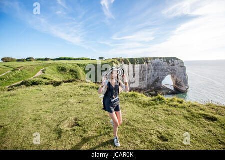 Giovane donna in striped hat e maglione godendo di una grande vista sulla famosa costa rocciosa nei pressi di Etretat città in Francia Foto Stock