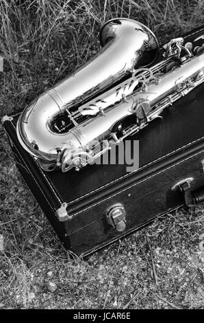 Il sassofono è su una valigia nella segale. Foto in bianco e nero Foto Stock