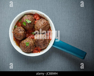 Gustose condite le polpette di carne in una casseruola con un caldo peperoncino piccante e la salsa di pomodoro e le erbe fresche, vista aerea Foto Stock