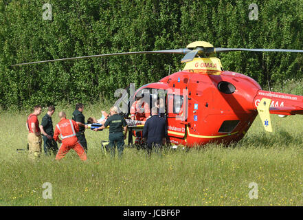 West Midlands Air Ambulance equipaggio di medici e paramedici NHS sollevamento di un incidente stradale paziente nell'elicottero Regno Unito Foto Stock