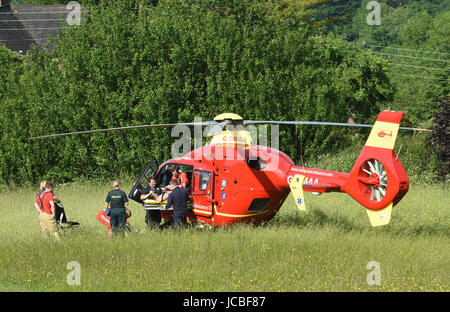 West Midlands Air Ambulance equipaggio di medici e paramedici NHS sollevamento di un incidente stradale paziente nell'elicottero Regno Unito Foto Stock