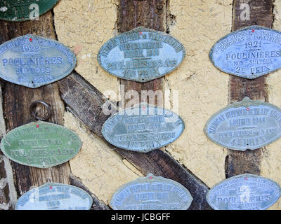BEUVRON-en-Auge, Francia - 6 agosto 2014: i badge commemorativa in onore di successi in concorsi di produttori di sidro dall inizio del XX secolo in Normandia sidro rotta Foto Stock