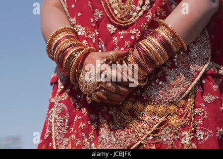 Le mani di un indiano sposa adornata con gioielli schiave e verniciati con colore henné. Foto Stock