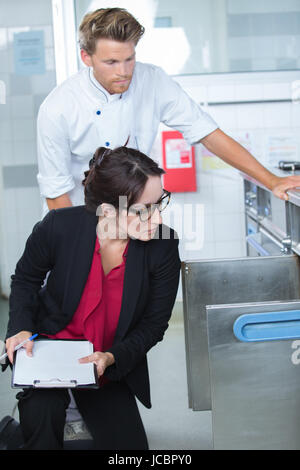 Ispettore esaminando le scorte di cibo nel ristorante cucina accompagnata dallo chef Foto Stock