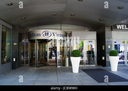 VIENNA, Austria - Aprile 30th, 2017: il logo sopra l'ingresso principale dell'Hotel Hilton Vienna Hotel in Wien, cinque stelle Hotel Hilton vicino al verde parco della città Foto Stock