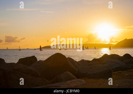 Piccole barche a vela in mare con grande sky con frondose nuvole sopra il golden sunset mare e rocce Foto Stock