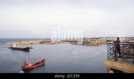 Ragazza cercando di Grand Harbour e Senglea con navi in esso da Upper Barrakka Gardens, Valletta, isola di Malta Foto Stock
