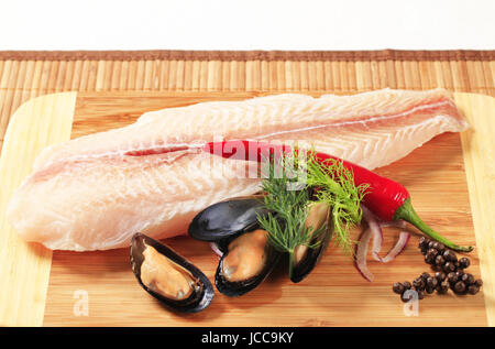 Pesce fresco e filetto di cozze su un tagliere Foto Stock