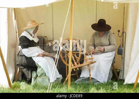 Le donne la filatura in un accampamento presso un Nodo sigillato guerra civile inglese rievocazione storica evento. Charlton park di Malmesbury, Wiltshire, Regno Unito Foto Stock