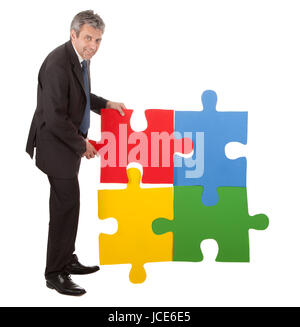 Imprenditore senior di assemblaggio di un puzzle. Isolato in bianco Foto Stock