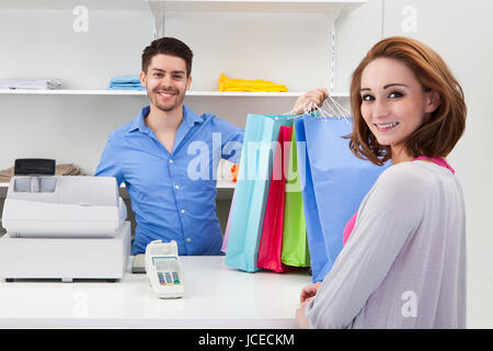 Felice cassiere maschio Consegna Shopping bag per il cliente Foto Stock