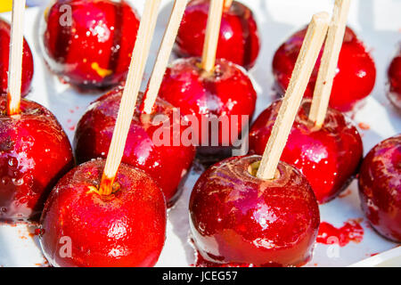 Caramellata mele rosso su bianco dei bastoni di legno. Foto Stock
