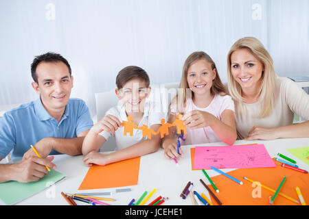 Ritratto di famiglia felice azienda persone di carta in mano a casa Foto Stock