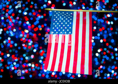 Bandiera americana appeso di fronte celebrativo sfondo bokeh di fondo in rosso, bianco e blu Foto Stock