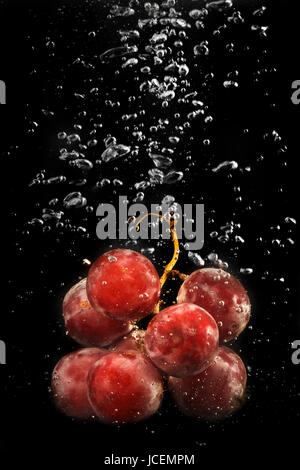 Le uve rosse nell'acqua,acqua splash Foto Stock