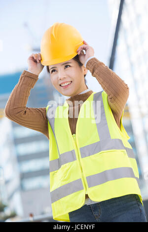 Donna sorridente operaio edile Foto Stock